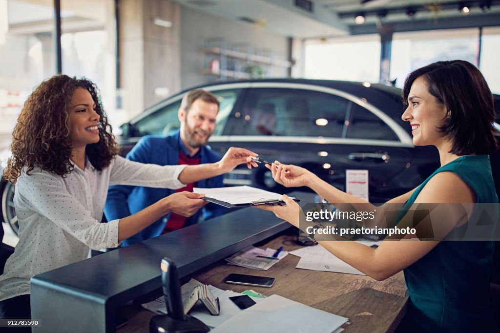 Couple is buying new car and signing the contract