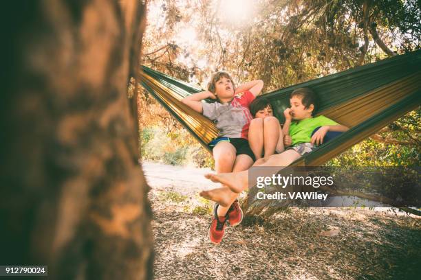 children relax while camping in a hammock - kicking tire stock pictures, royalty-free photos & images