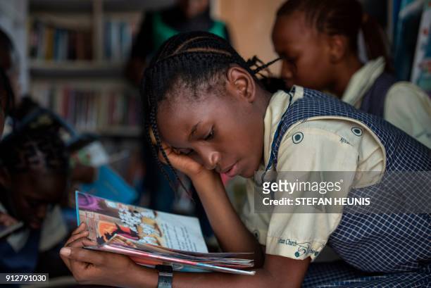 Girl reads through a book in the I-Read mobile library on January 30, 2018. The I-Read initiative is the first mobile library service in Nigeria. AFP...