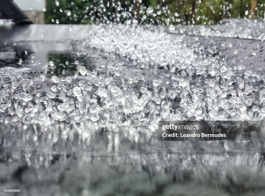 Raindrops jumping about car hood.