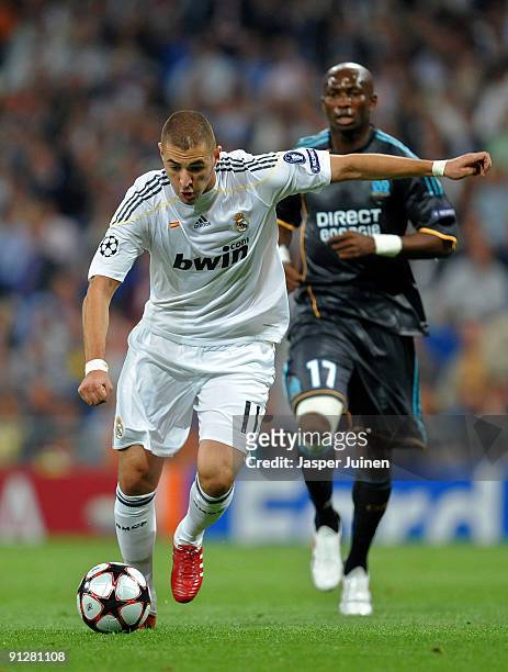 Karim Benzema of Real Madrid runs with the ball tracked by Stephane Mbia of Marseille during the Champions League group C match between Real Madrid...
