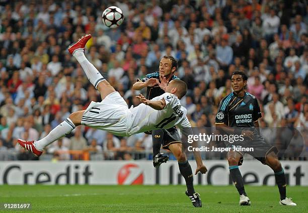 Karim Benzema of Real Madrid tries to score with an overhead kick against Laurent Bonnart and Fabrice Abriel of Marseille during the Champions League...