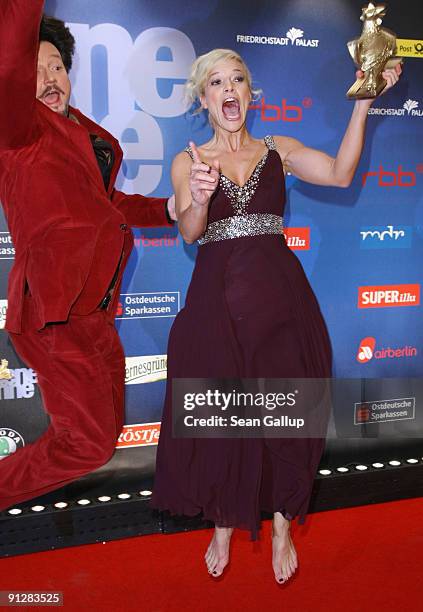 Television presenter Ina Mueller holds her Goldene Henne Award while jumping with star chef Kolja Kleeberg at the Goldene Henne 2009 awards at...