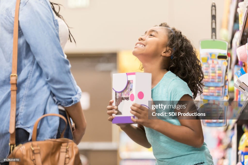 Kleines Mädchen bittet ihre Mutter um ein Spielzeug zu kaufen