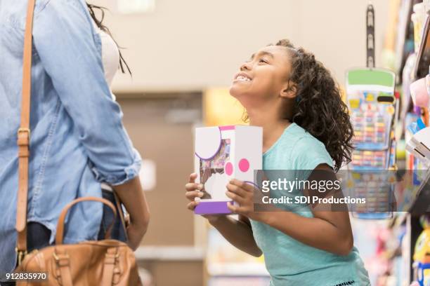 little girl begs her mom to buy a toy - suplicar imagens e fotografias de stock