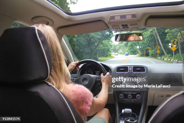 woman driving car with sunroof open - armaturenbrett stock-fotos und bilder