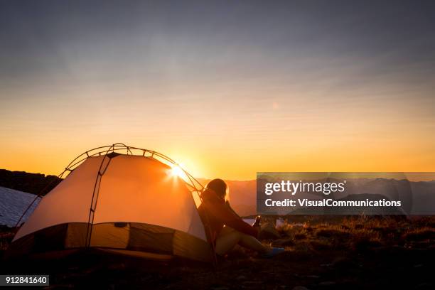 woman sitting in tent looking at sunset. - watching sunset stock pictures, royalty-free photos & images