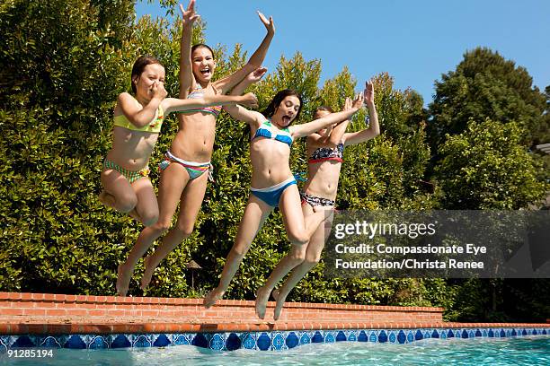 four girls in bathing suits jumping into a pool - young teen bathing suit stock pictures, royalty-free photos & images