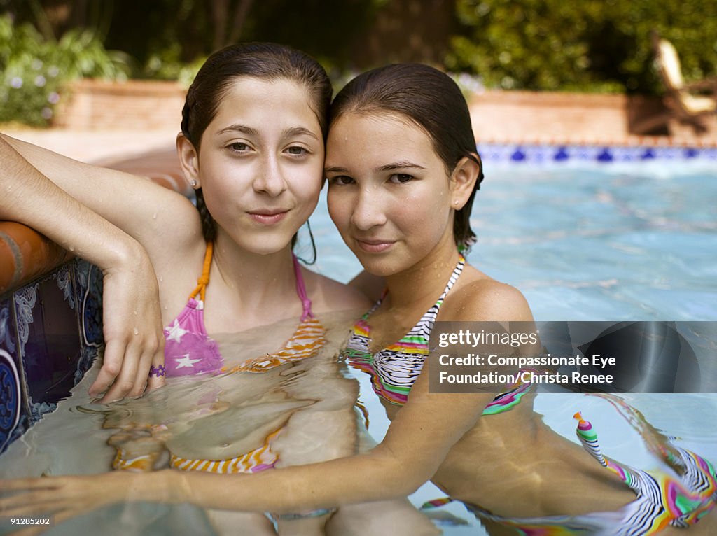 Two young girls in bathing suits in a pool