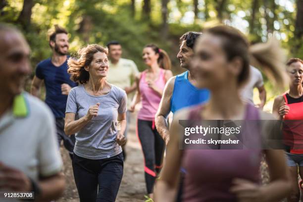 felice coppia matura che parla mentre corre una maratona attraverso la foresta. - 10000 metri foto e immagini stock