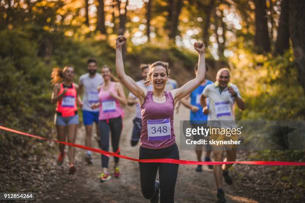 feminino alegre corredor wining maratona e cruzando a linha de chegada. - meia maratona - fotografias e filmes do acervo