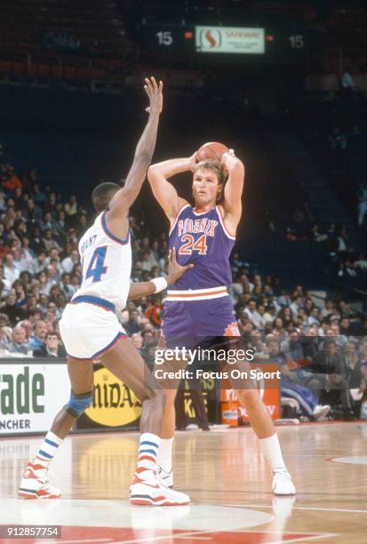 Tom Chambers of the Phoenix Suns looks to pass the ball over the top of Harvey Grant of the Washington Bullets during an NBA basketball game circa...