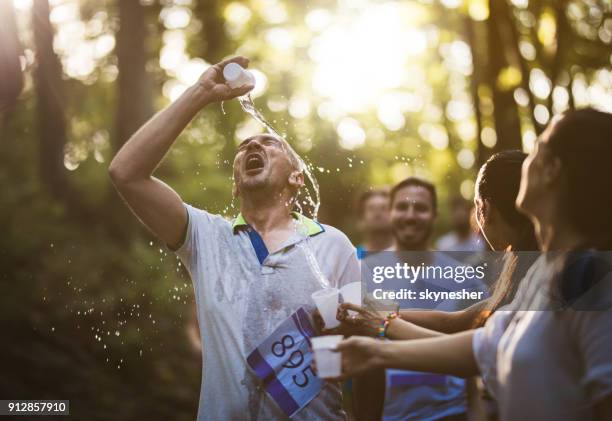 male marathon runner refreshing himself while pouring water on his face. - 10000m stock pictures, royalty-free photos & images