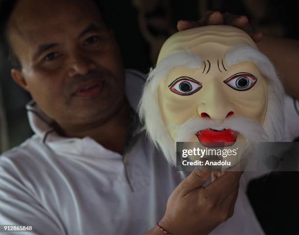 Made Budhatama holds a wooden mask at his workshop in Ubud regency of Bali, Indonesia on January 30, 2018. Made has been carving masks for a living...