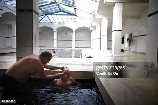 Dursun Gungor helps peel the dead skin off of his brother Aslan's face a psoriasis patient from Germany in a mineral-rich spring full of 'doctor...