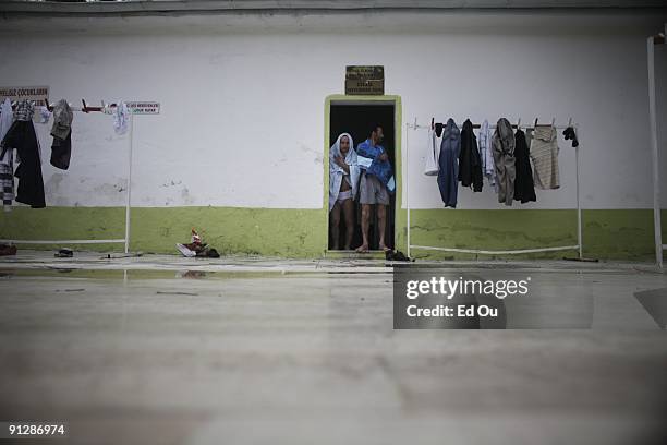 Turkish men hide from frain after bathing in a mineral-rich pool full of 'doctor fish', on September 13, 2009 in Kangal, 105 kilometers south of the...