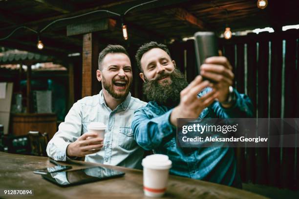 zwei bärtigen freunde, trinken kaffee und nehmen selfie in kaffee - movember stock-fotos und bilder