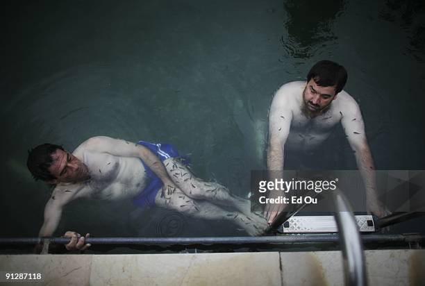 Turkish men bathe in a mineral-rich pool full of 'doctor fish', on September 13, 2009 in Kangal, 105 kilometers south of the central Turkish city of...