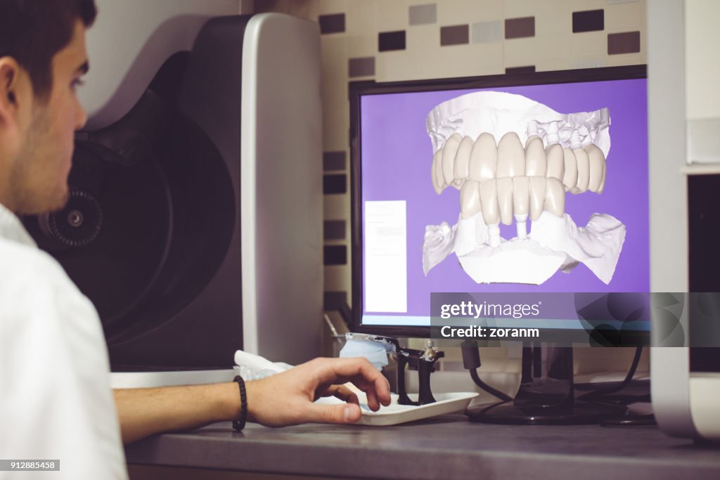 Protésico dental usando computadoras para operar equipo dental