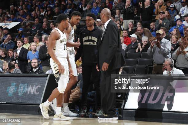 Wake Forest's Doral Moore is consoled by Bryant Crawford , former Wake Forest player and current Atlanta Hawks player John Collins and head coach...