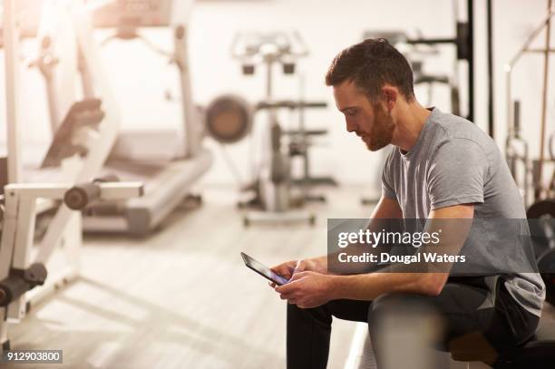 man using digital tablet in gym after exercising. - sport tablet stockfoto's en -beelden