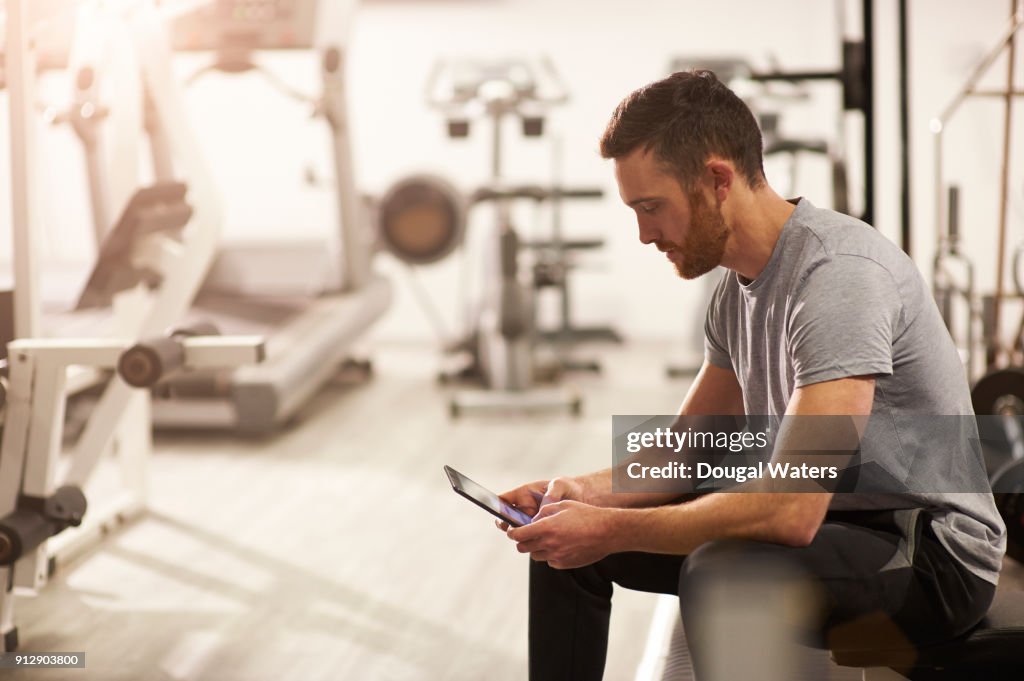 Man using digital tablet in gym after exercising.