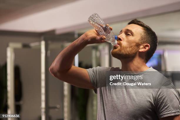 man in gym drinking water. - bottle water sport stock-fotos und bilder