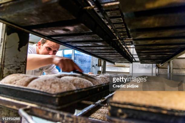 baker is preparing bread for the oven - baker stock pictures, royalty-free photos & images