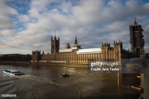 Boats pass the Houses of Parliament along the River Thames on February 1, 2018 in London, England. MPs have voted to leave the Palace of Westminster...