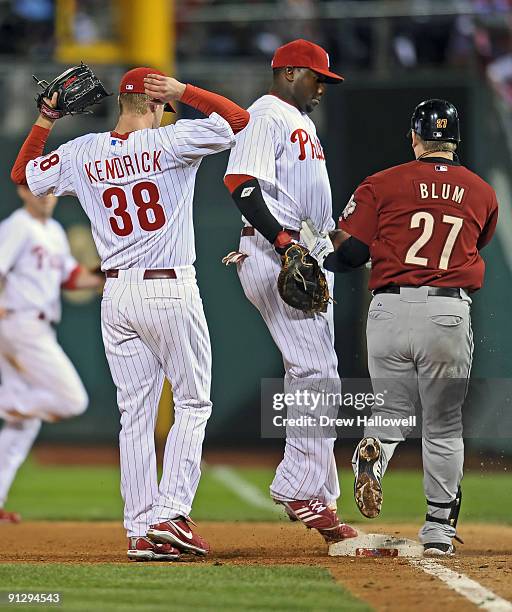 Kyle Kendrick of the Philadelphia Phillies gets out of the way while teammate Ryan Howard steps on first base to put out Geoff Blum of the Houston...