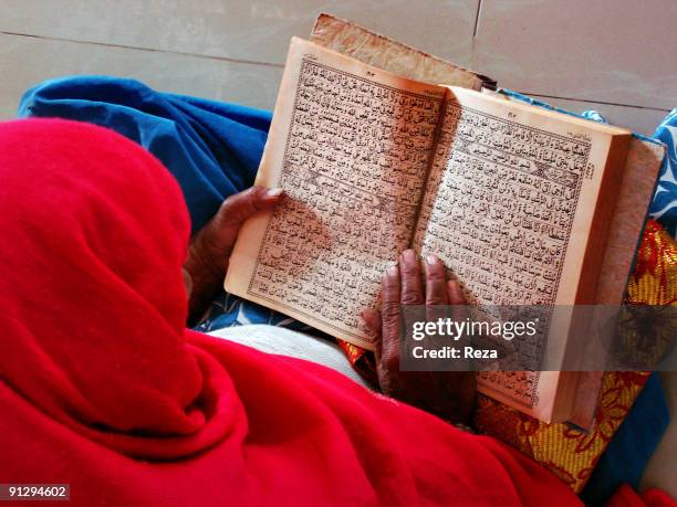 Portrait of a woman reading the Quran inside the shrine of Bodla Bahhar, one of the main disciples of Lal Shahbaz Qalandar, a 13th century Sufi...