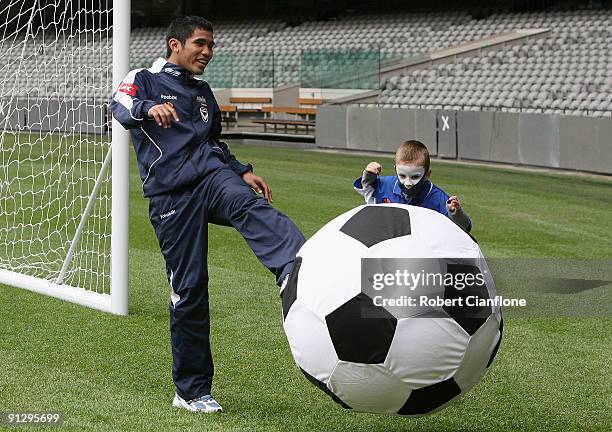 Victory player Surat Sukha kicks a large ball with children during a media conference to promote the round 10 A-League match between the Melbourne...