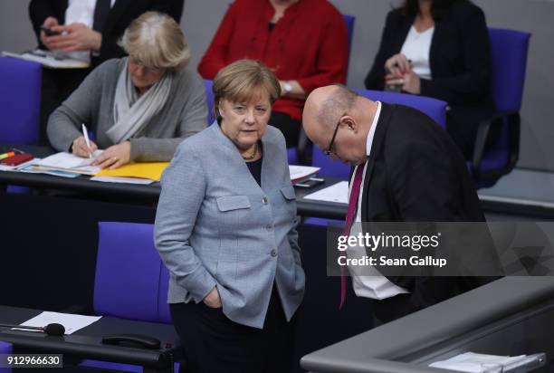 German Chancellor Angela Merkel chats with Interim Finance Minister Peter Altmeier during debates at the Bundestag over a proposal concerning the...