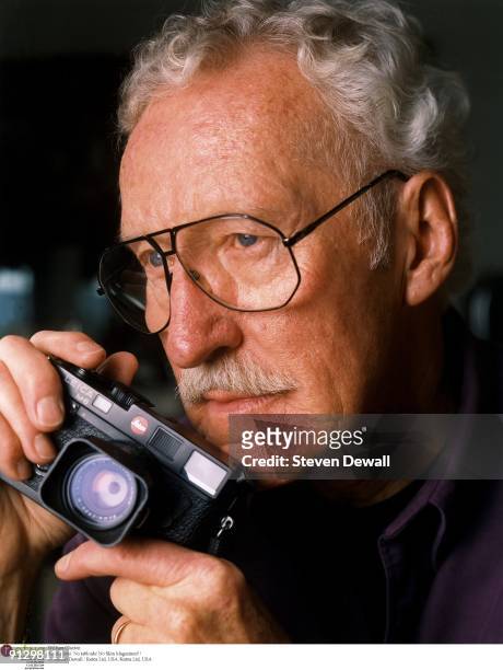 Jazz photographer William Claxton poses with a Leica camera at his home in 2000 in Los Angeles, California, United States.