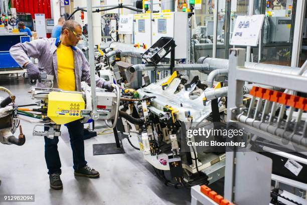 Worker uses machinery to work on bodywork for VW Polo automobiles on the production line at the Volkswagen AG plant in Uitenhage, South Africa, on...