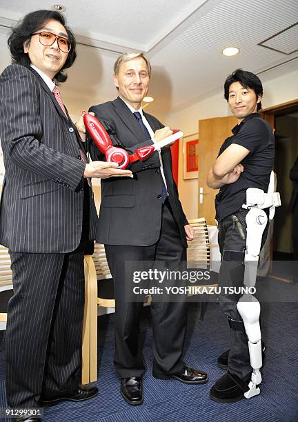 Japan's Tsukuba University professor Yoshiyuki Sankai poses with the newly developed power assisted elbow next to Franz-Michael Mellbin , Danish...