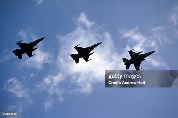 three fighter jets in silhouette against sky - avion militaire photos et images de collection