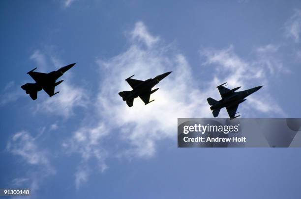 three fighter jets in silhouette against sky - caccia-aereo-militare foto e immagini stock