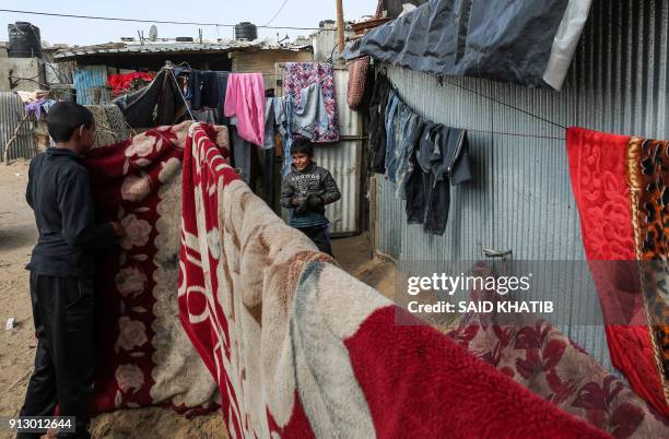 Palestinian children stand outside their makeshift homes between the laundry lines with blankets and clothes hung out to dry, in the Rafah refugee...