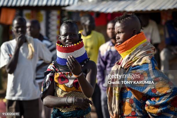 Women in elaborate neck adornements from the local Turkana community look on at Kalobeyei refugee settlement scheme in Kakuma, a collaborative effort...