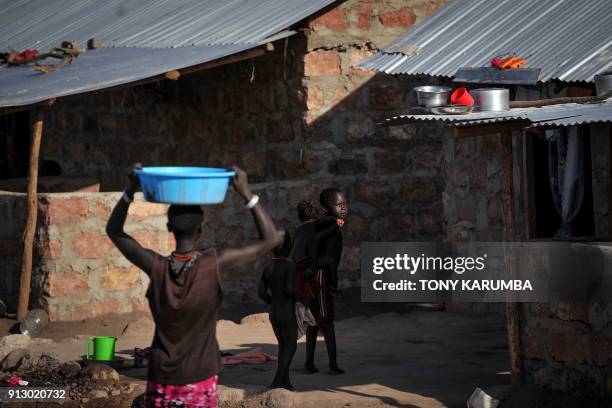 Children play as a woman carries a pail of water on her head at Kalobeyei refugee settlement scheme in Kakuma, a collaborative effort by the UNHCR...