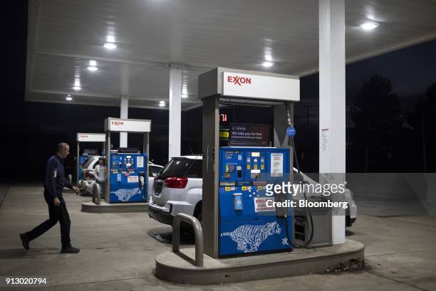 An attendant walks towards a vehicle in front of fuel pump at an Exxon Mobil Corp. Gas station in Nashport, Ohio, U.S., on Friday, Jan. 26, 2018....