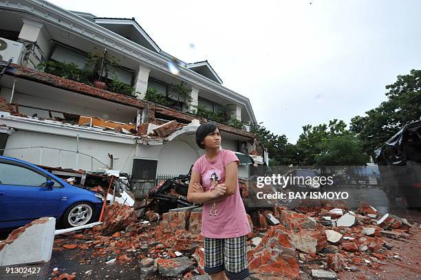 Woman stands next to a colapse hotel in Padang, West Sumatra, on October 1, 2009 after a 7,9 strong earthquake hits the area. Thousands of people...