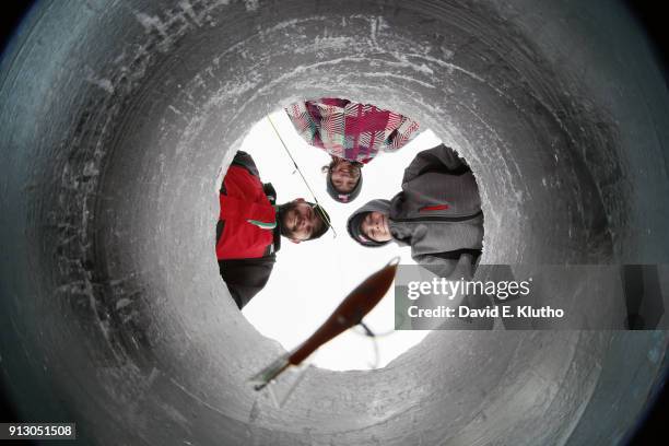 Brainerd Jaycees Ice Fishing Extravaganza: View from below of committee chair Shane Meyer with his children lowering bait down hole into water during...