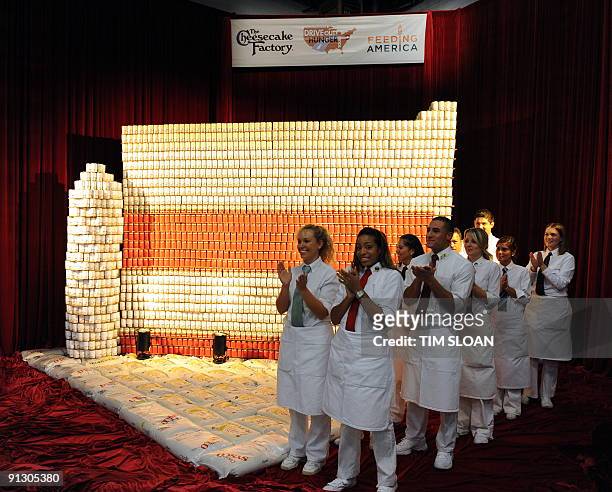 Local area Cheese Cake Factory employees applaud the unveiling of a world record-sized sculpture made entirely of 30,000 cans of soup in the shape of...