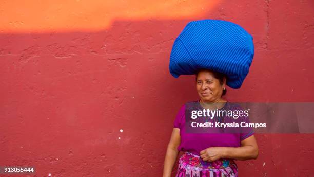 senior mayan woman in typical costume with bundles balanced on her head. antigua - guatemala. - maya guatemala stock pictures, royalty-free photos & images