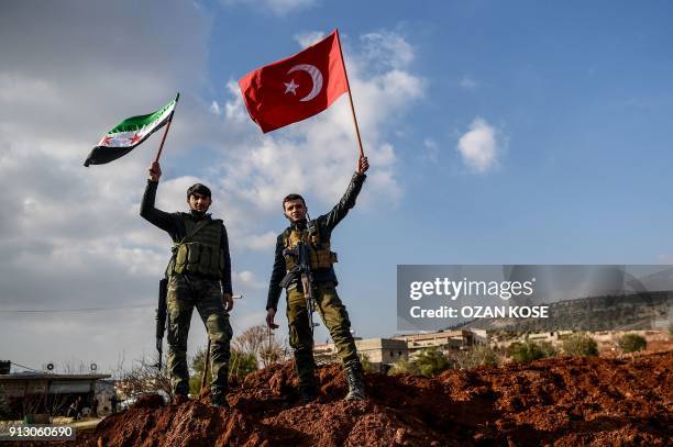 Turkish-backed Syrian rebel fighters hold Turkish national flag and Free Syrian Army flags at a checkpoint in the Syrian town of Azaz on a road...