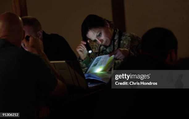 Navy sailor studies a textbook by flashlight at an outdoor seating patio during the evening on October 1, 2009 in Bagram, Afghanistan. Bagram Air...