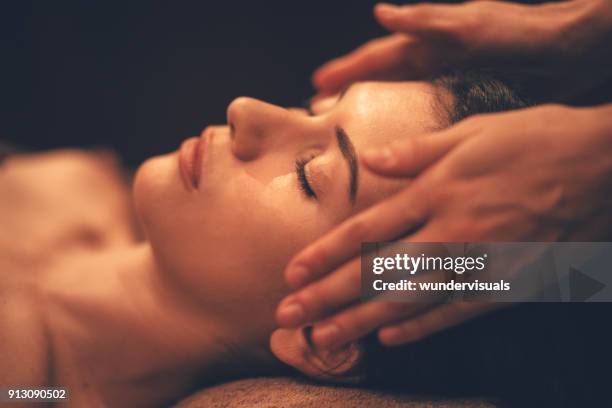 jonge vrouw hoofdmassage krijgen op dag spa salon - masseren stockfoto's en -beelden