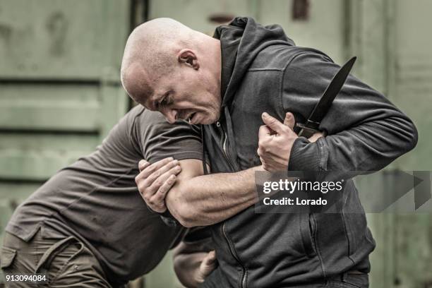 krav maga fighting duo sparring during training session in grimy outdoor setting - krav maga stock pictures, royalty-free photos & images